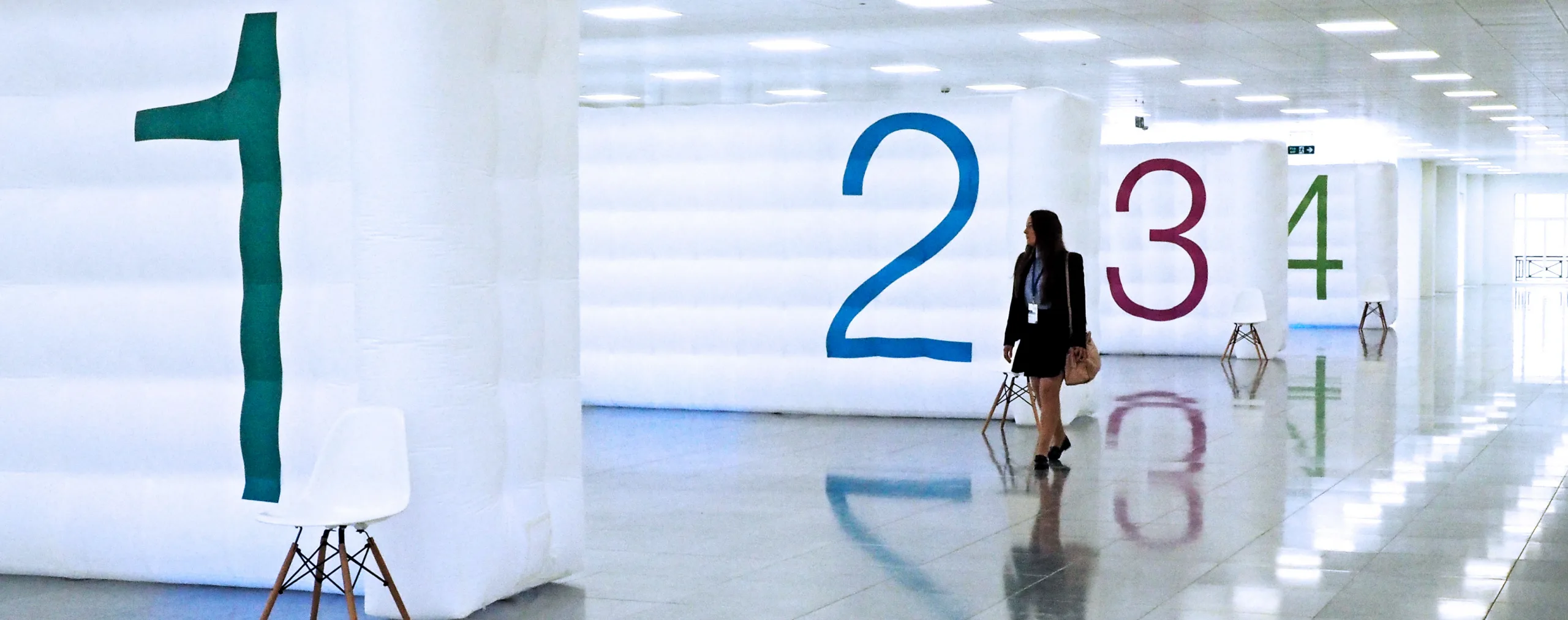 Pic showing several Created By Air inflatable walls used to divide a space. The walls have the numbers 1, 2, 3, 4. A woman is walking by