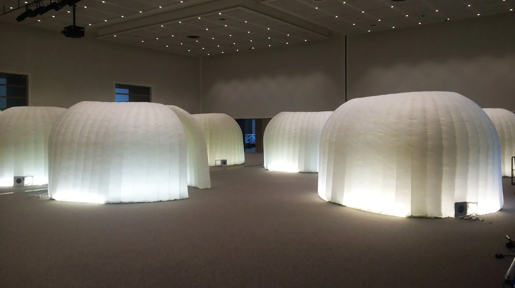 Pic showing several Created By Air inflatable office pods installed as enclosed breakout rooms at an indoor event